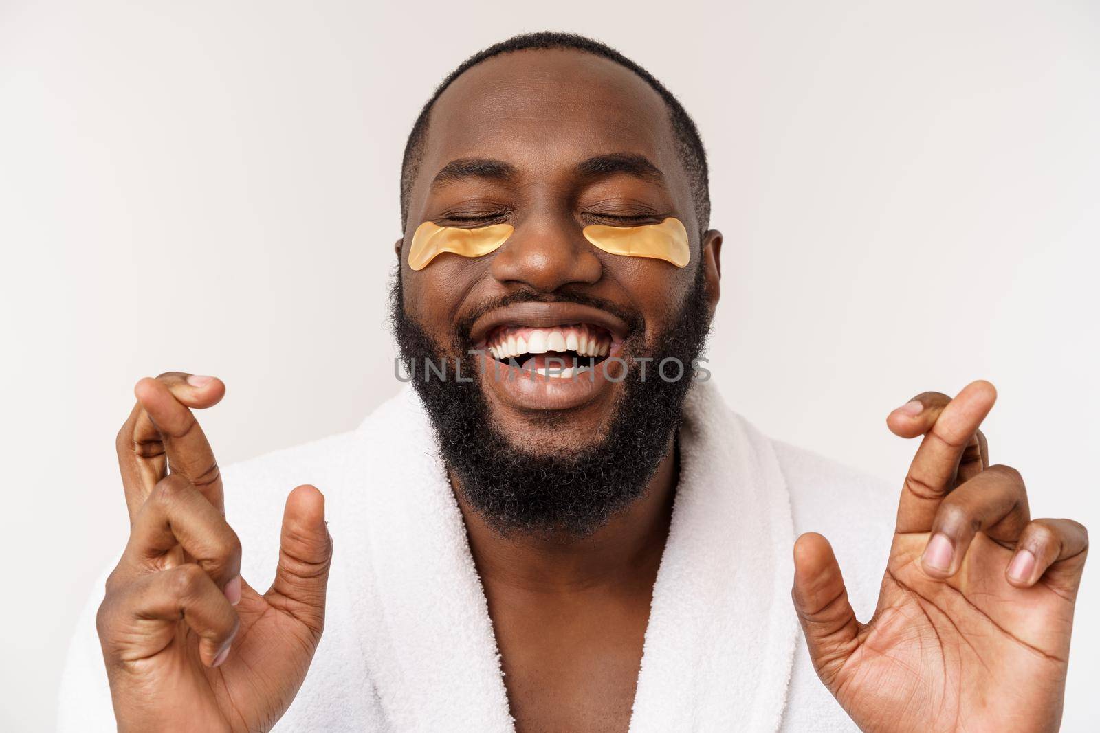 A young man with paper eyes mask on face looking shocked with an open mouth, isolated on a white background