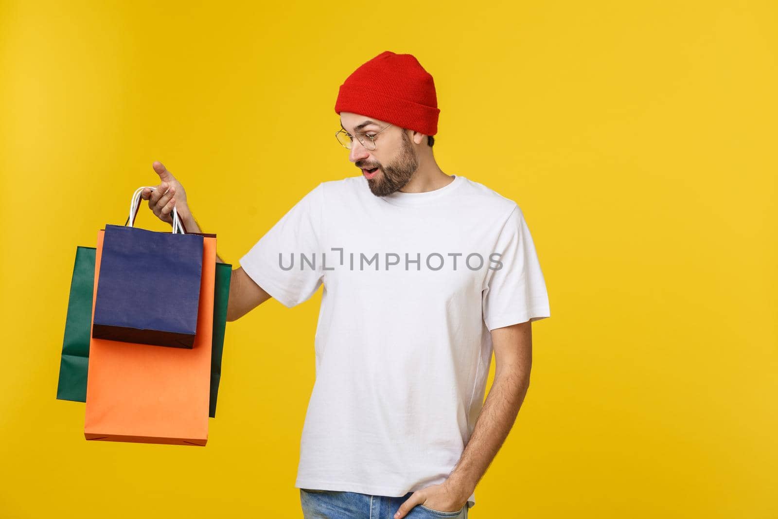 Bearded man with shopping bags with happy feeling isolated on yellow bacground.