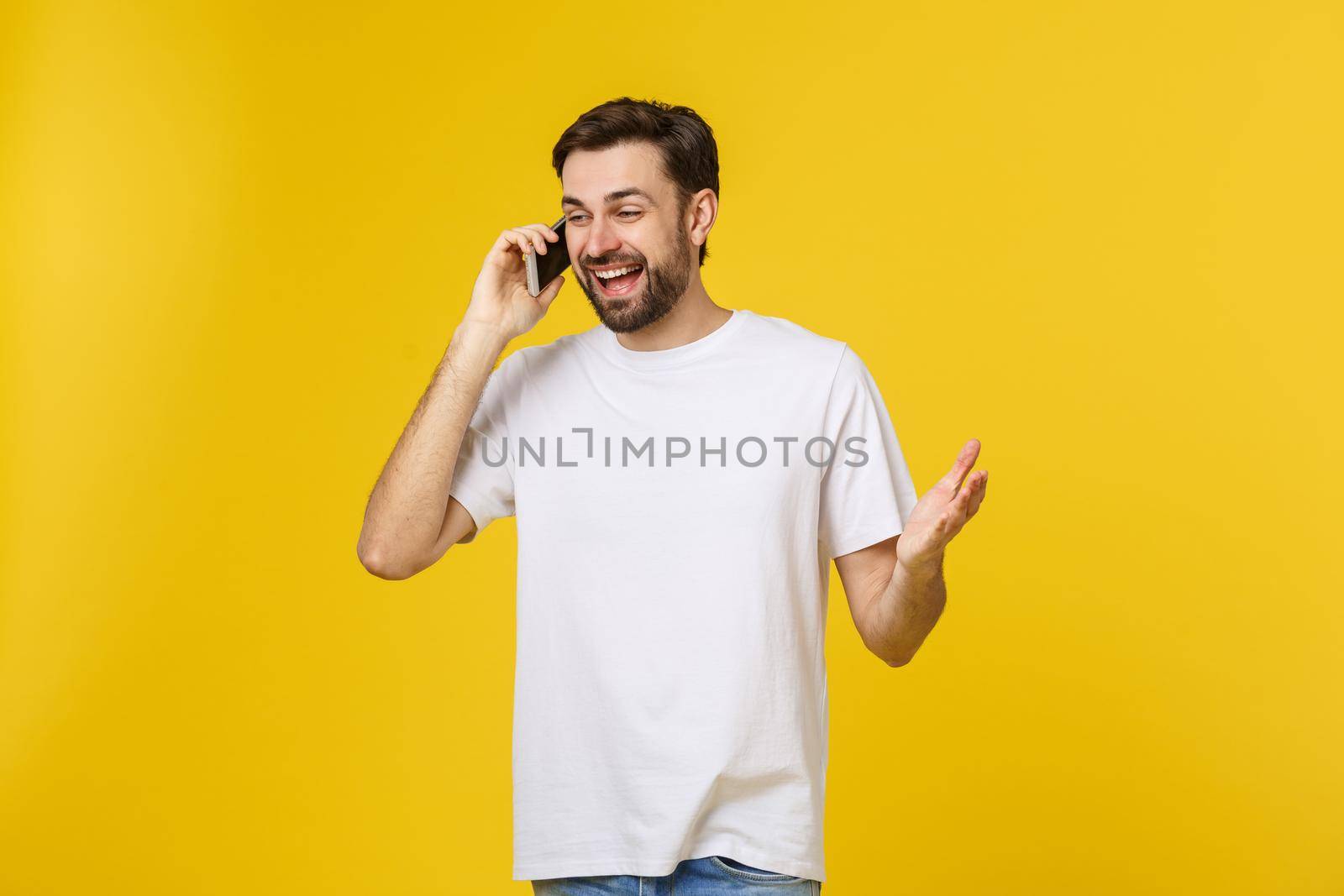 young casual man talking on the phone isolated on yellow background.