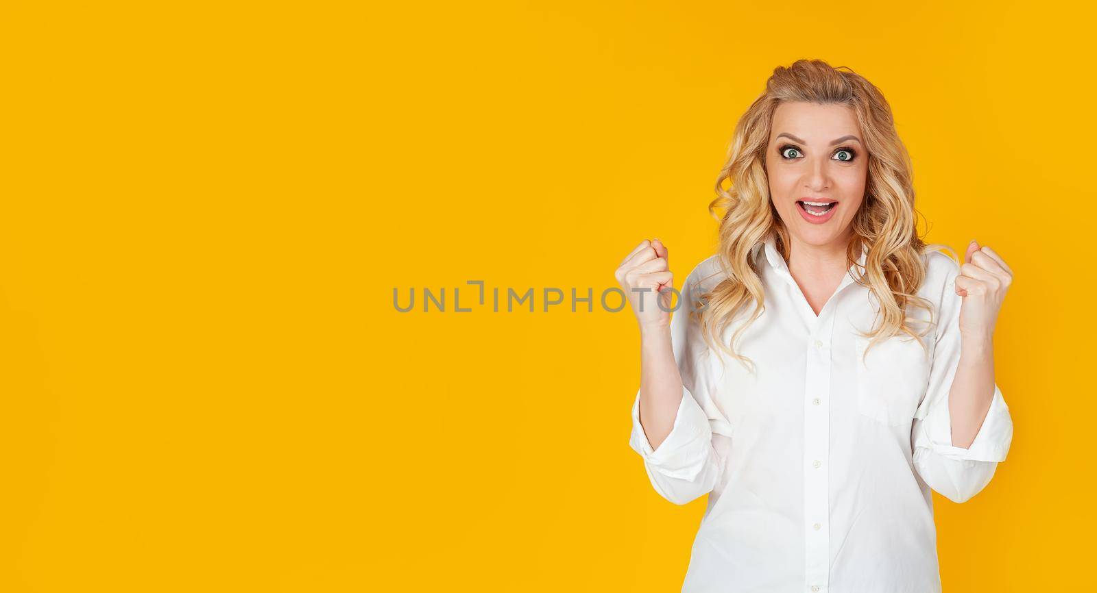The concept of tension, games and emotions. An encouraged, excited pretty woman in a white shirt, rooting for the team, made a big bet and screamed, come on TV, clenched fists and screaming,
