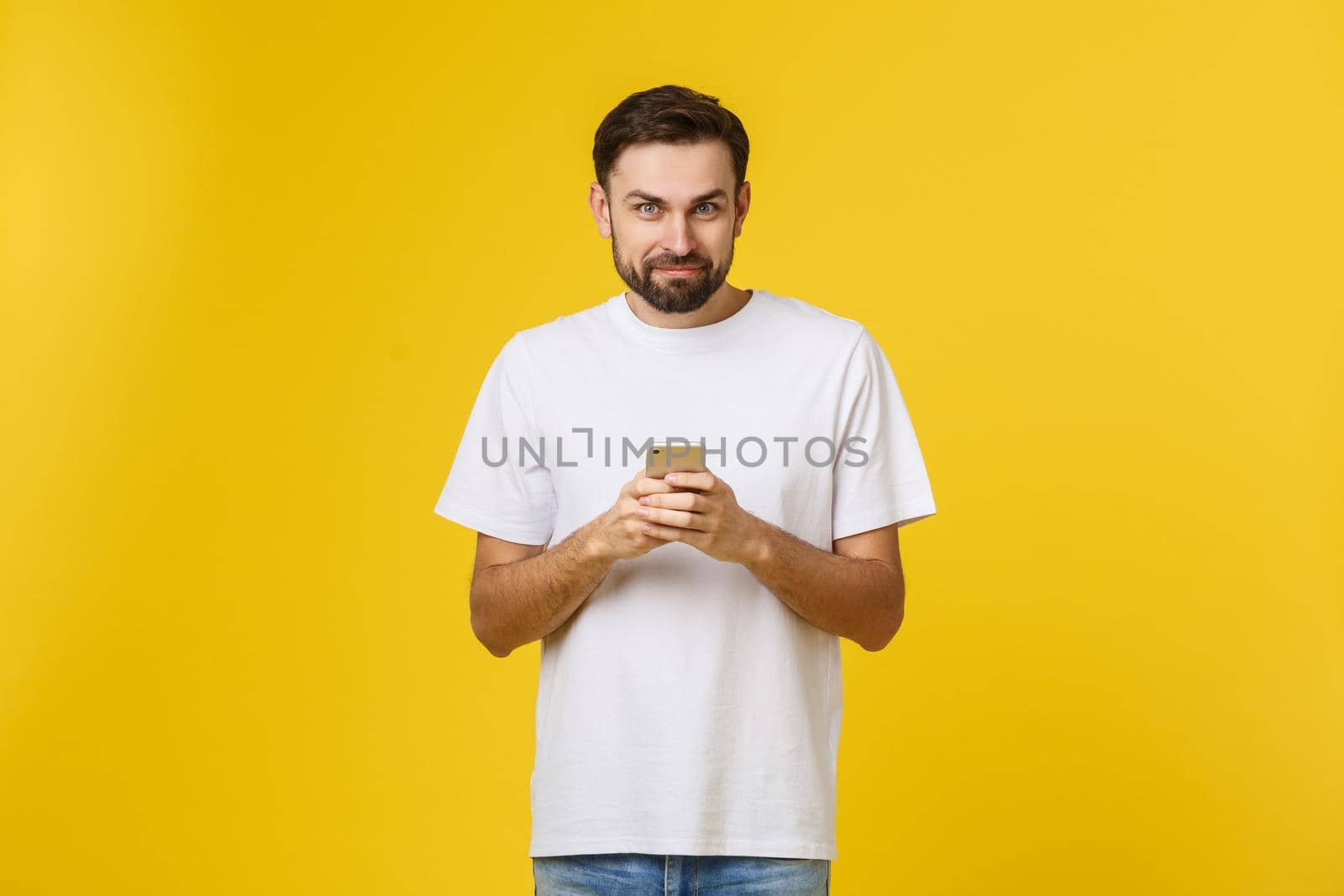 Portrait of a serious man talking on the phone isolated on a yellow background. Looking at camera.