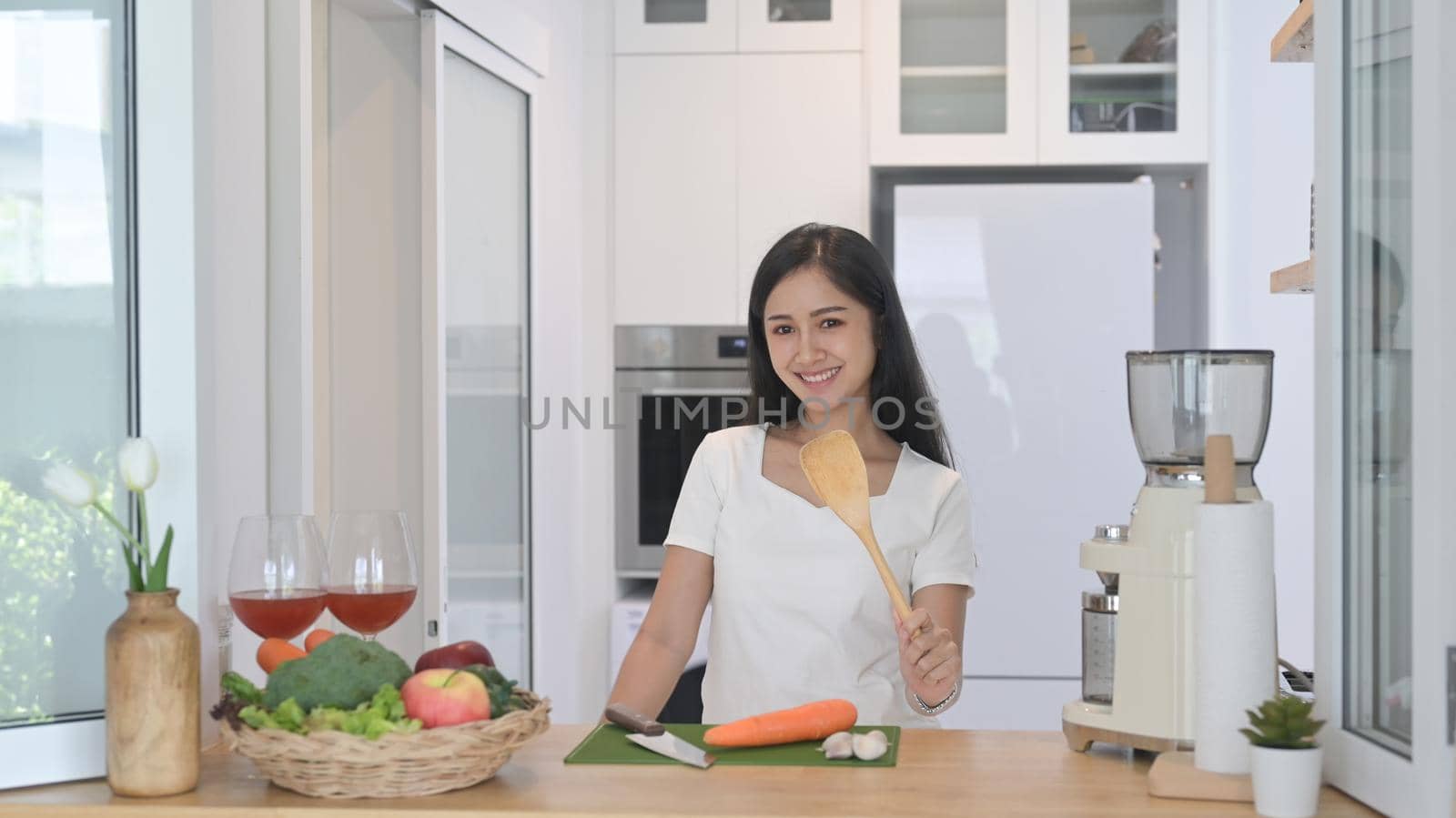 Cheerful asian standing at modern kitchen counter and preparing ingredient for making vegetarian food.