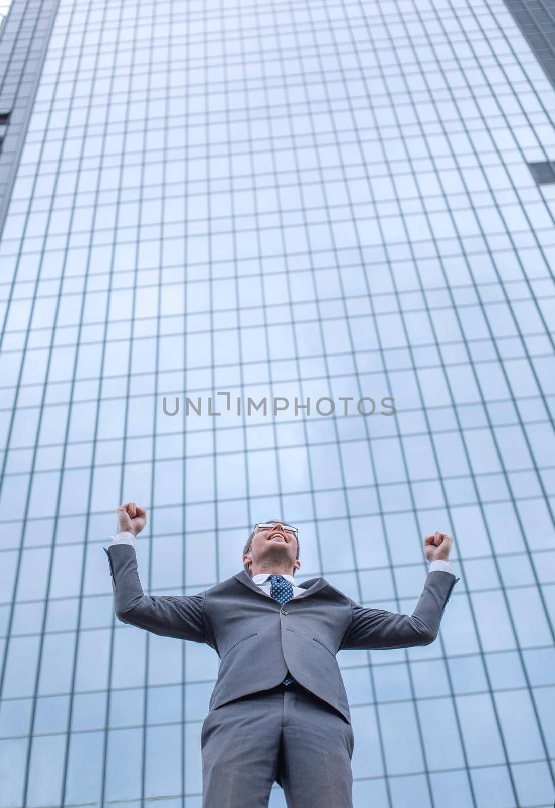 happy young businessman standing on the street and looking up . photo with copy space