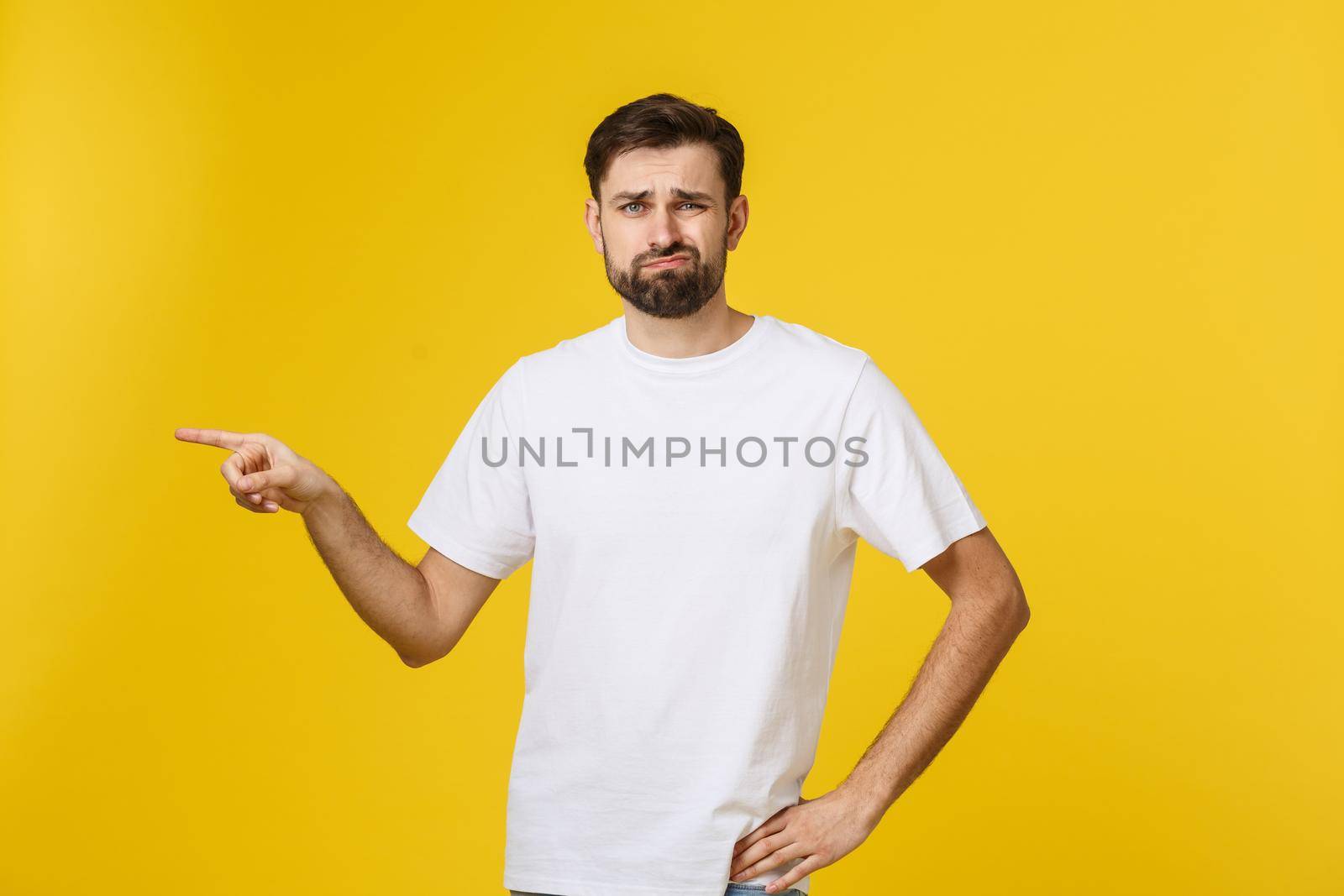 Handsome man over isolated yellow wall frustrated and pointing to the front