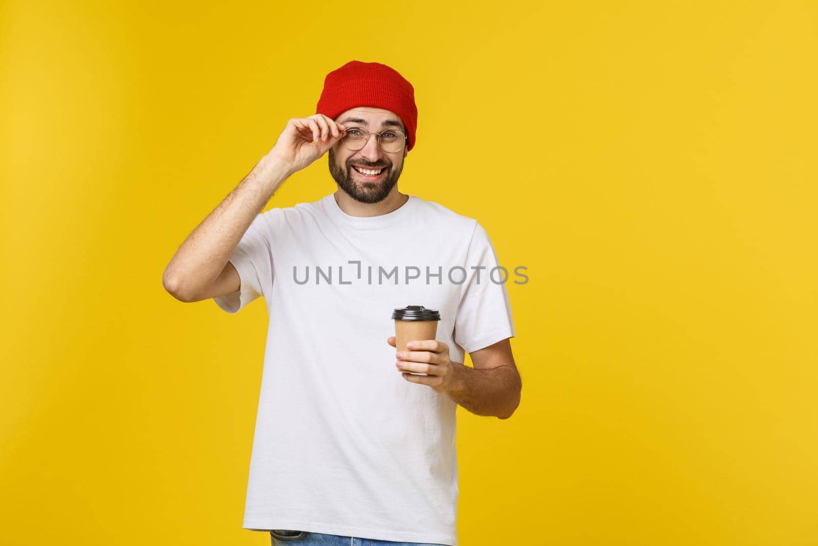 Man on isolated vibrant yellow color taking a coffee in takeaway paper cup and smiling because he will start the day well. by Benzoix