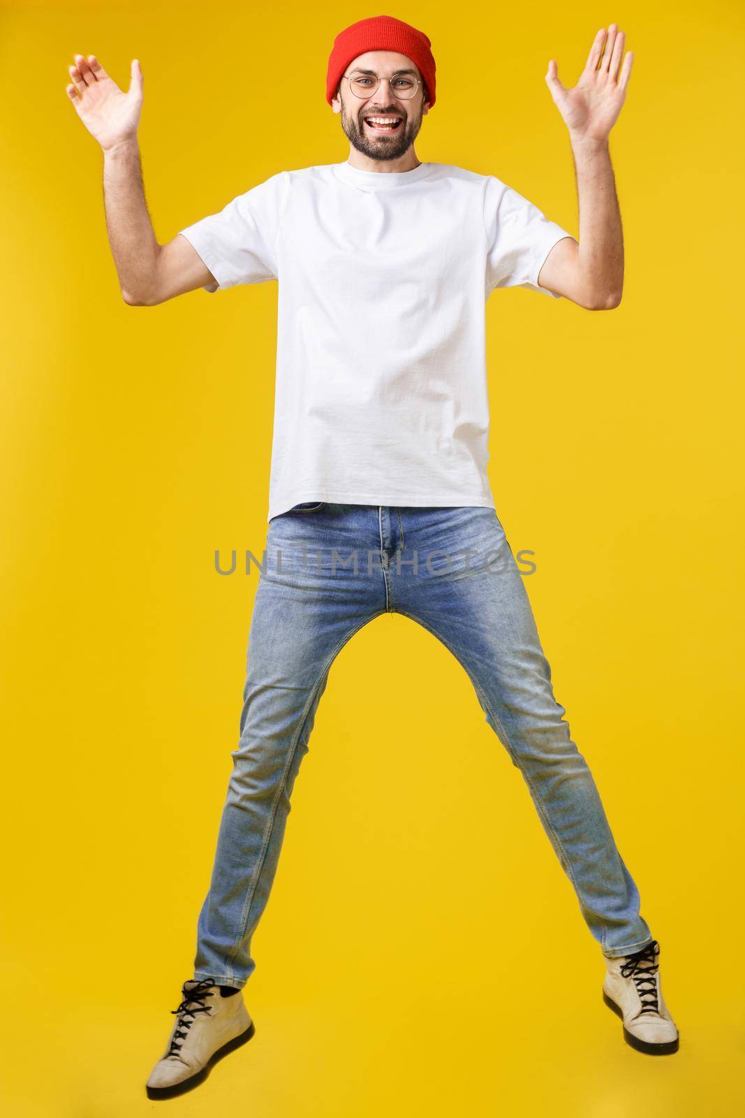 young casual man jumping for joy on yellow gold background by Benzoix