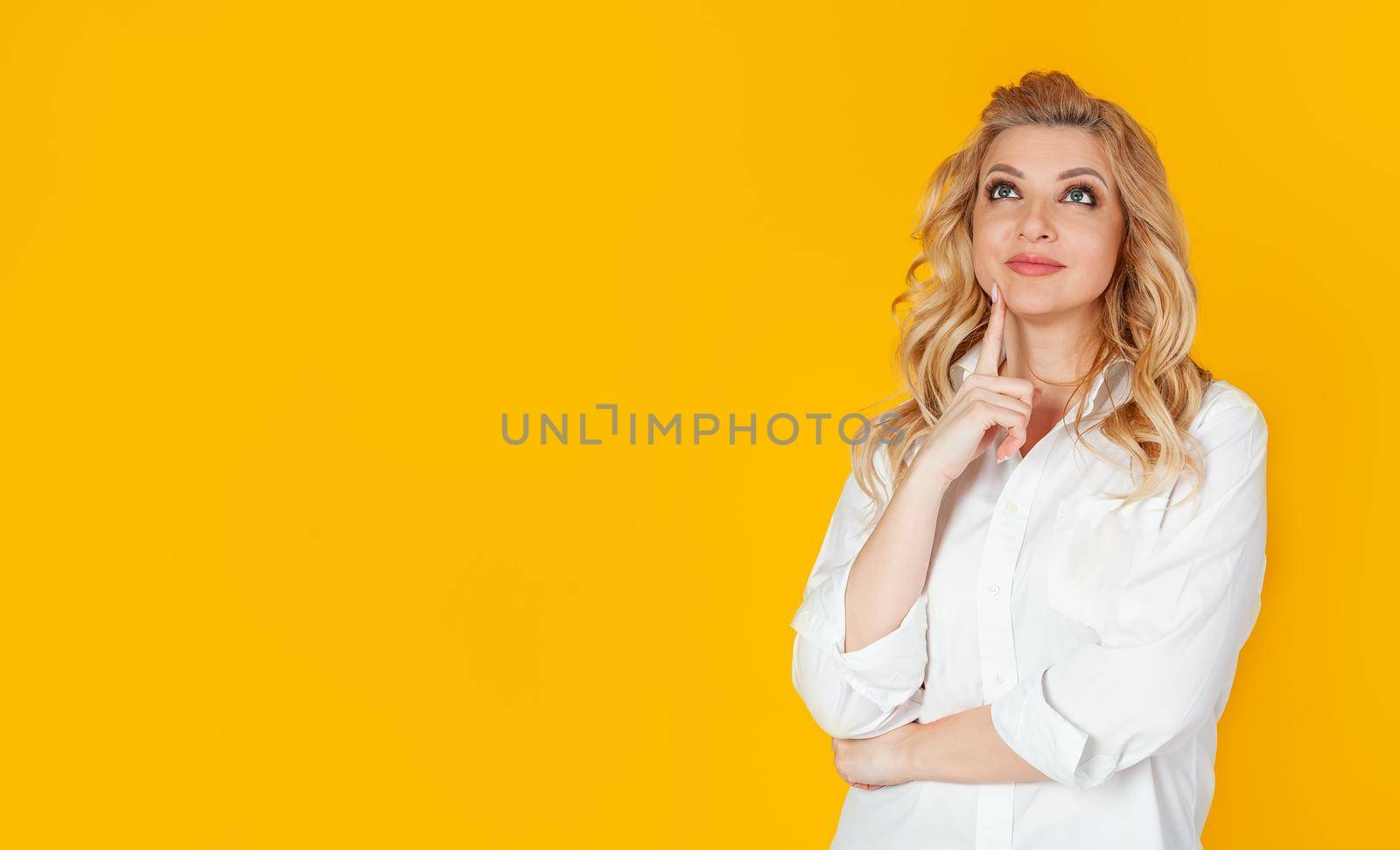 Curious modern stylish caucasian blond woman sideways look thinking make a choice thinking thinking delighted smile widely touching face thoughtful have an interesting idea desire