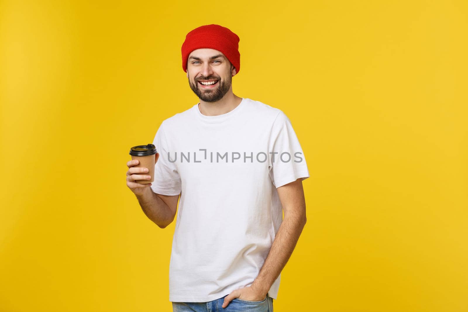 Man on isolated vibrant yellow color taking a coffee in takeaway paper cup and smiling because he will start the day well. by Benzoix