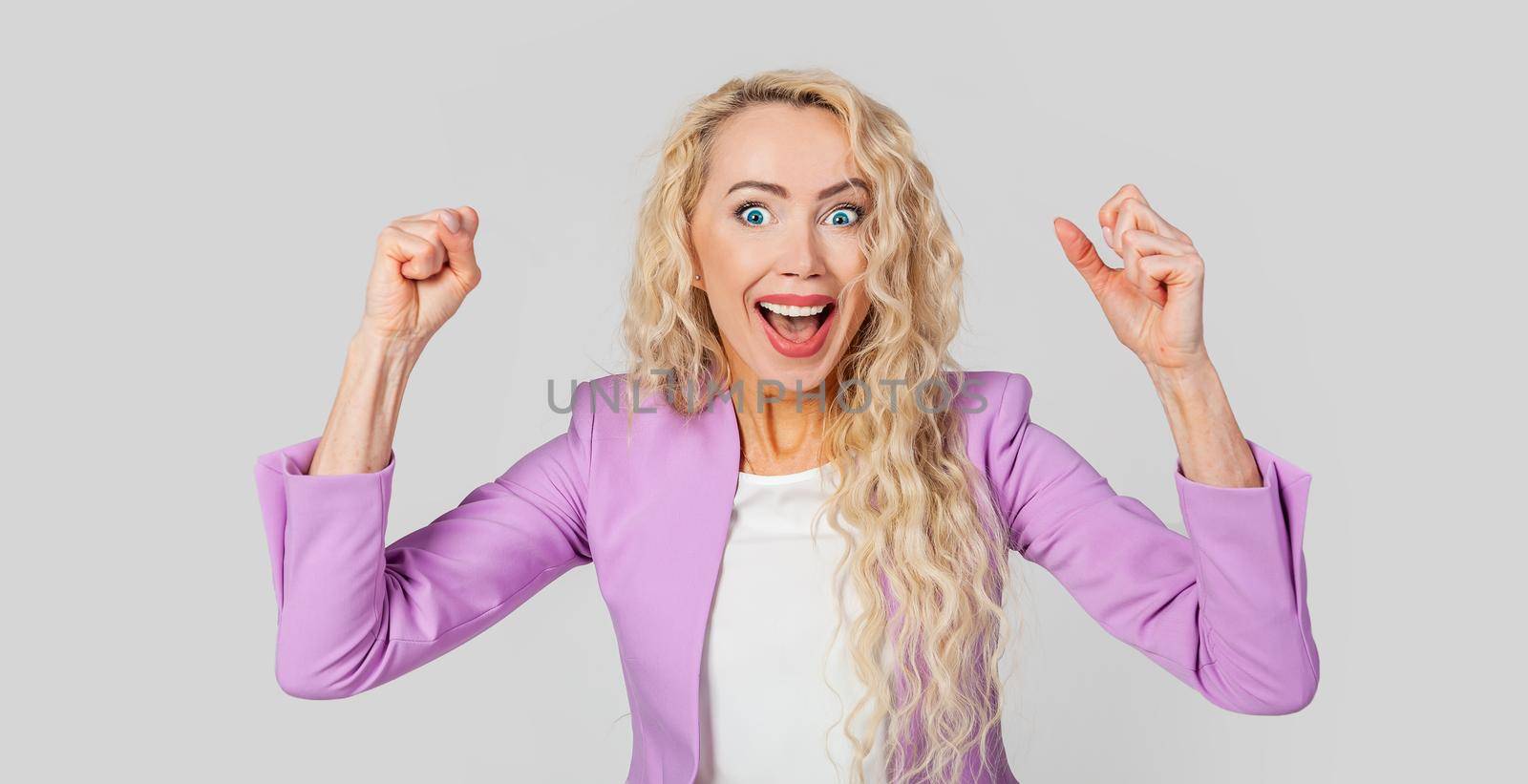 Cheerful, happy woman raising her hands with her fist, cheering for the team, winning a huge bet, playing in the casino in delight, cheering friends, watching football
