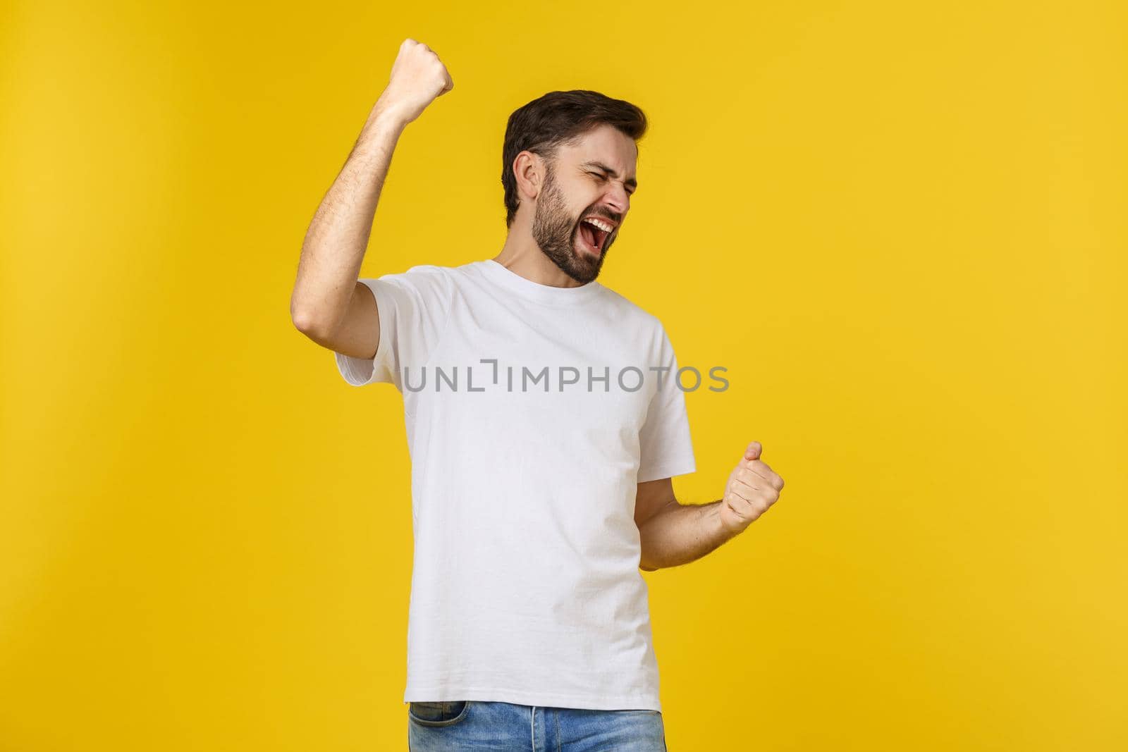 Happy young man with arms up isolated on a yellow background