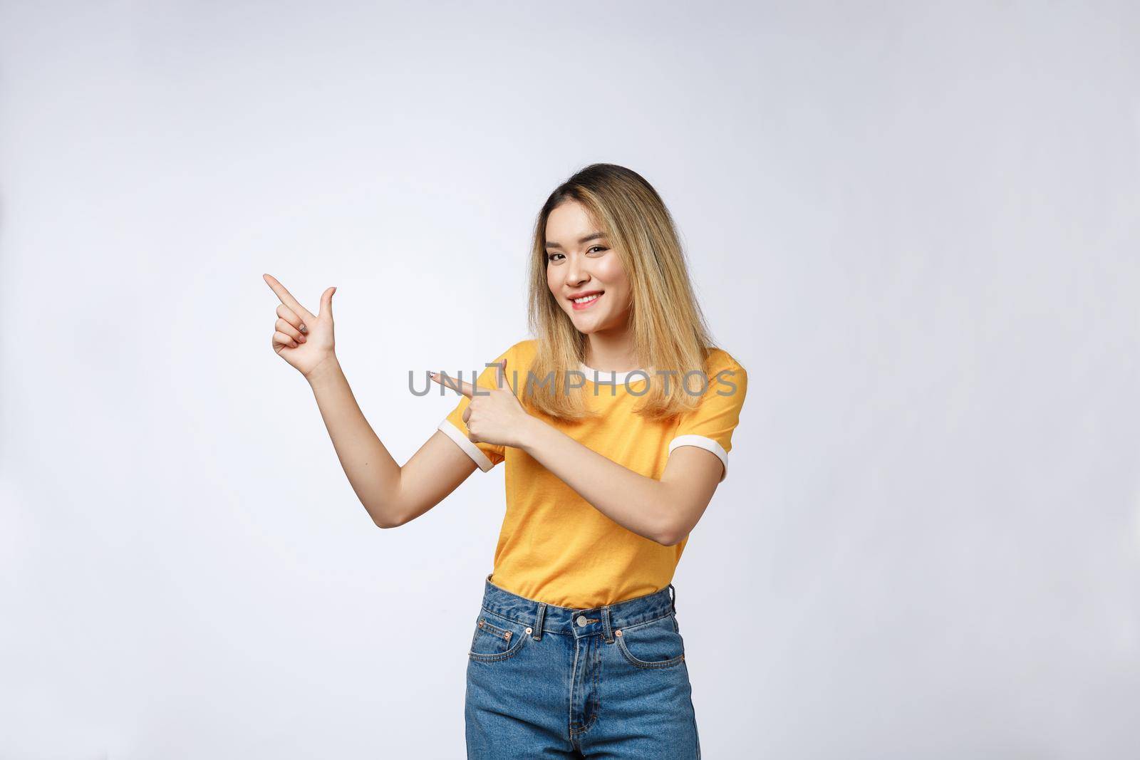 Beautiful young Asian woman pointing her finger up with cheerful expression, on white background