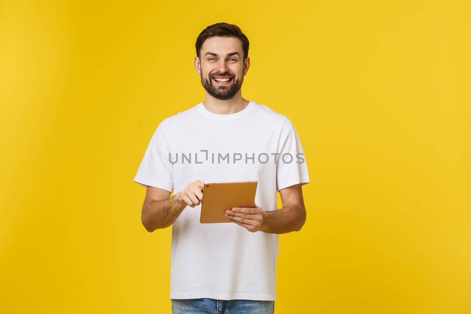 Attractive fashionable young Caucasian man working on touch pad pc, making presentation, using wireless high speed internet connection