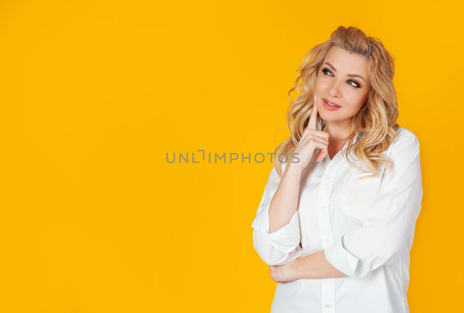 Curious modern stylish caucasian blond woman sideways look thinking make a choice thinking thinking delighted smile widely touching face thoughtful have an interesting idea desire
