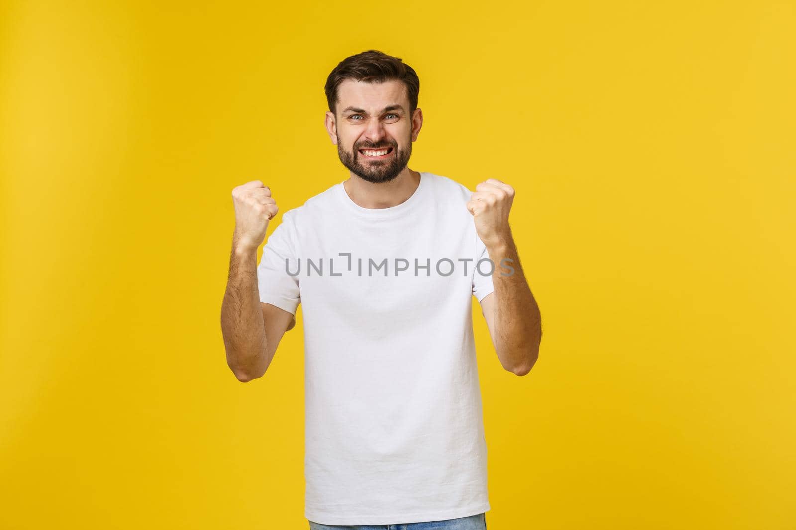 Happy young man with arms up isolated on a yellow background. by Benzoix