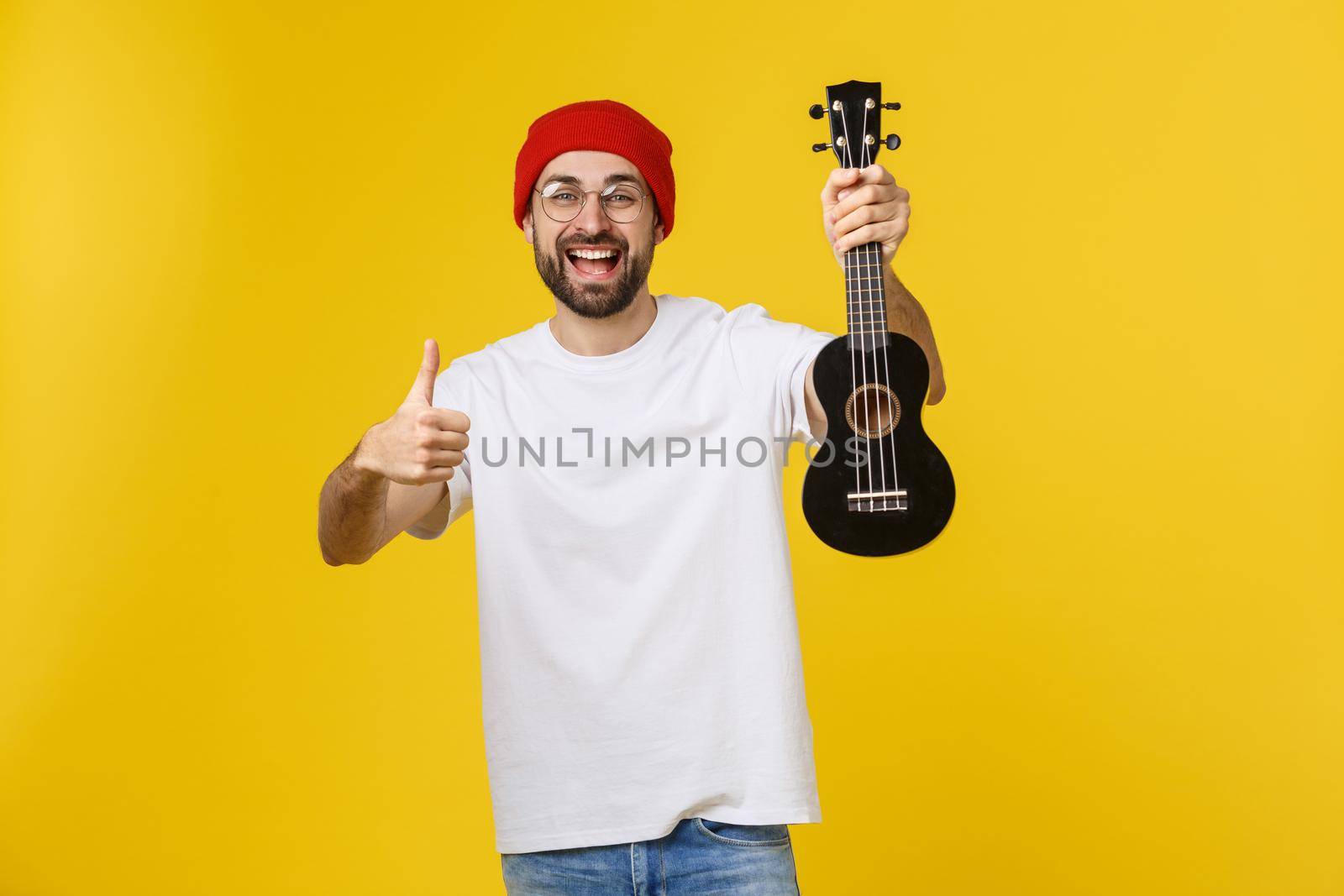 close-up of funny young man playing a guitar. isolated on yellow gold background by Benzoix