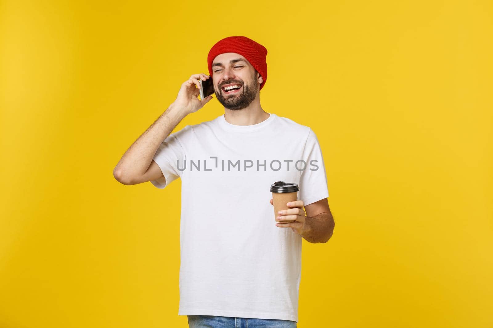 Man on isolated vibrant yellow color taking a coffee in takeaway paper cup and smiling because he will start the day well