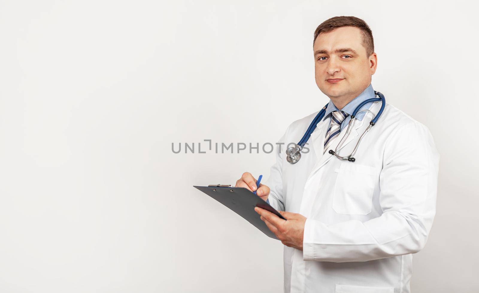 Men doctor writes with a pen a document on a tablet, writes a medical history. The concept of healthcare, medicine, and pharmacy.