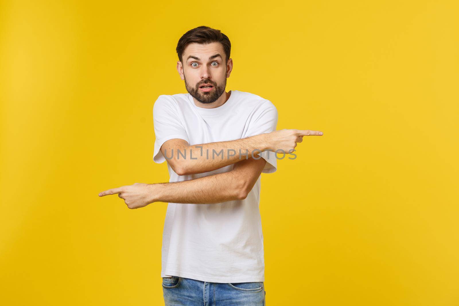 Handsome man over isolated yellow wall frustrated and pointing to the front