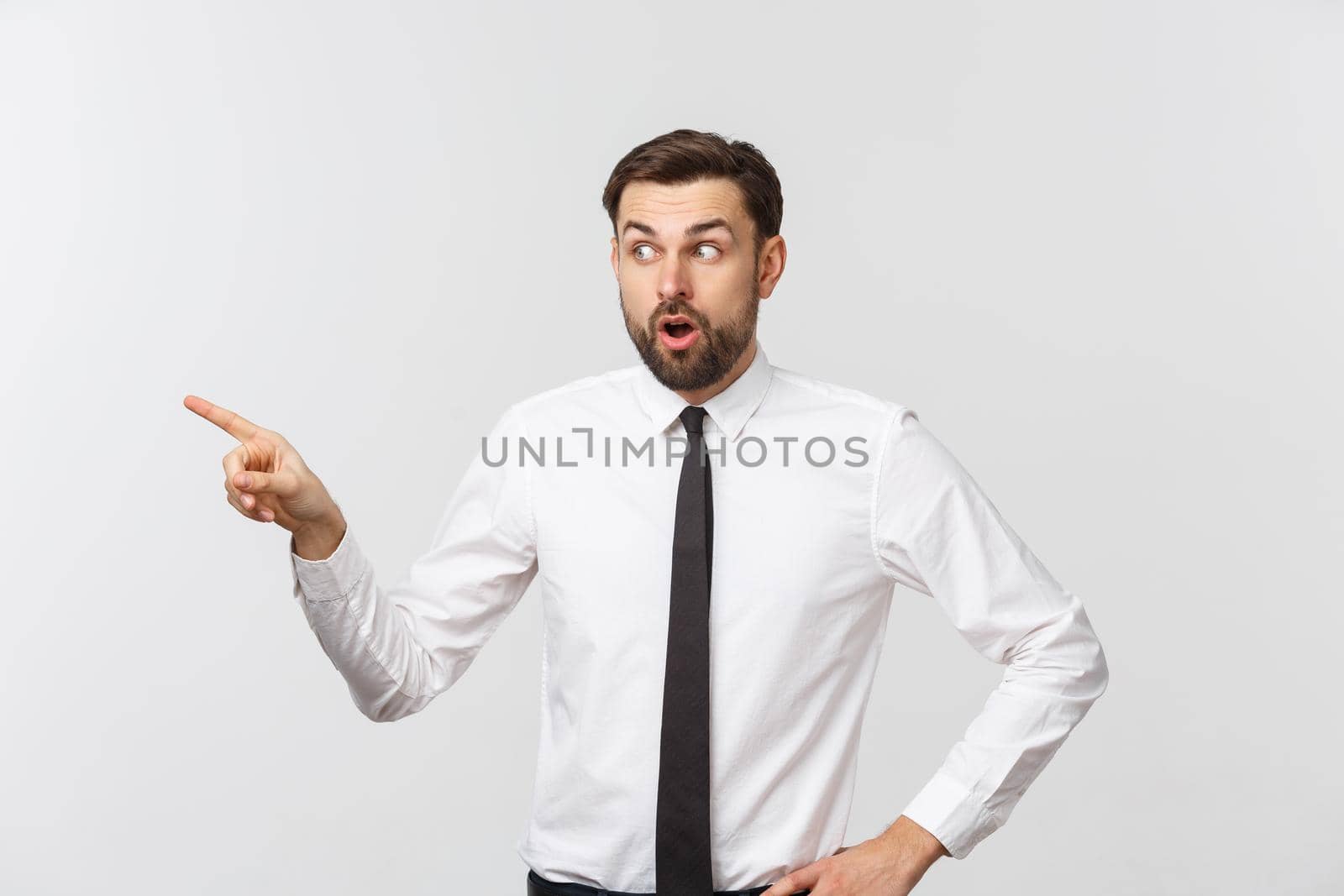 Young handsome businessman pointing to something using a finger. Isolated on white.