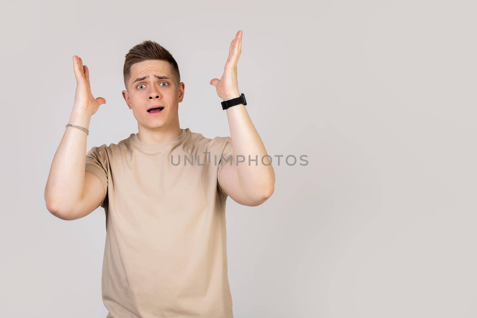 A handsome guy, a young man holding his head in his hands with happy excitement, cannot believe the good news