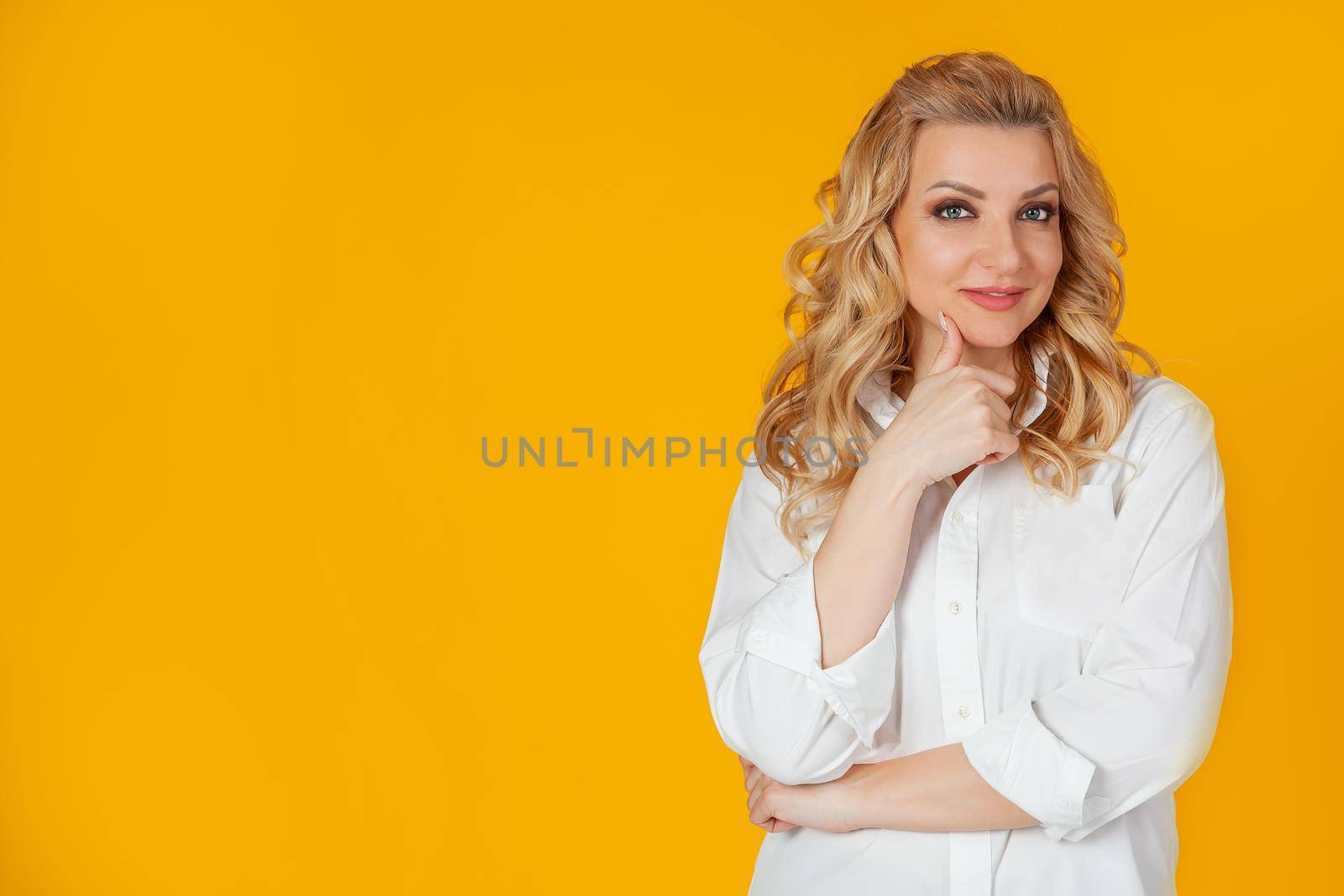 Smiling attractive happy and successful European woman blonde in a white shirt, smiling, expressing confidence, diligently and impudent looking at the camera with a bold smile