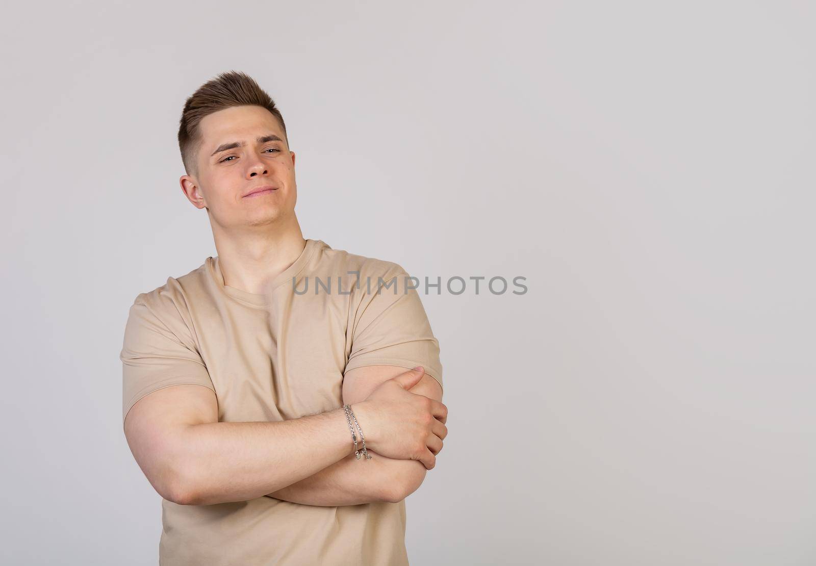 Handsome young man crossed his arms over his chest with an average expression on his face. Confident sports guy, showing off his achievements, looking at the camera. I feel great