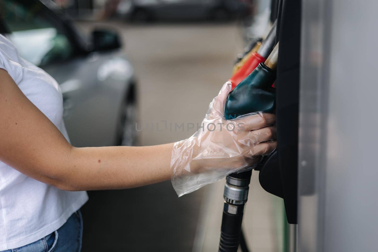 Close-up of a women's hand using a fuel nozzle at a gas station. Petrol station concept. Filling station at petrol gasoline.