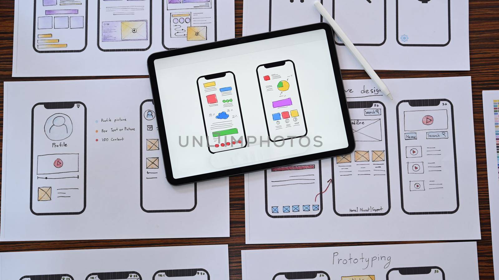Web developer workplace with sketches of mobile application on wooden table. Flat lay, Top view.