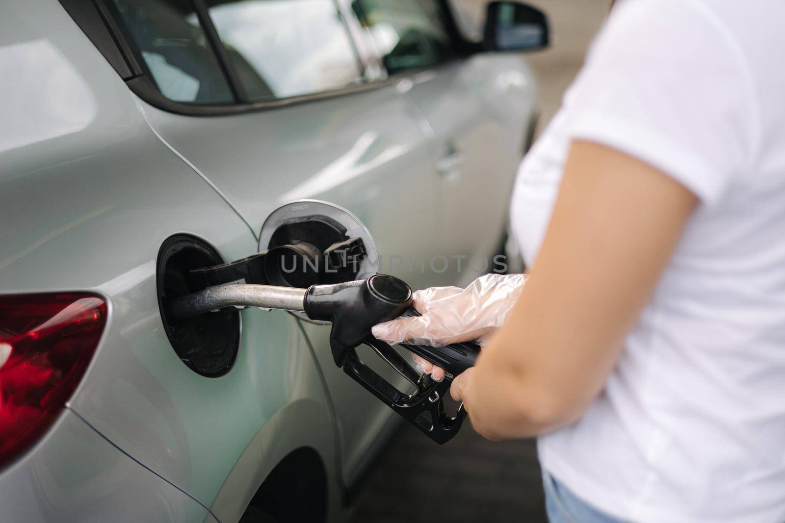 Woman is refueling at gas station. Female hand filling benzine gasoline fuel in car using a fuel nozzle. Petrol prices concept. Close-up of hand.