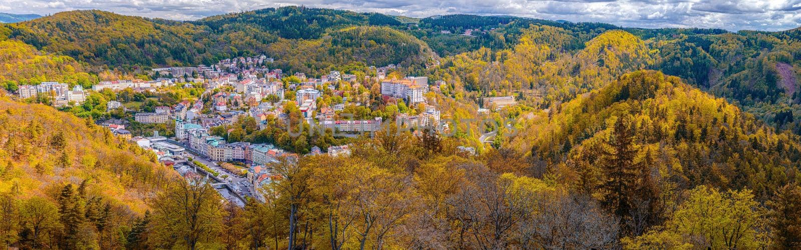 Karlovy Vary city aerial panoramic view with row of colorful multicolored buildings and spa hotels in historical city centre. Panorama of Karlsbad town and Slavkov Forest mountains in autumn