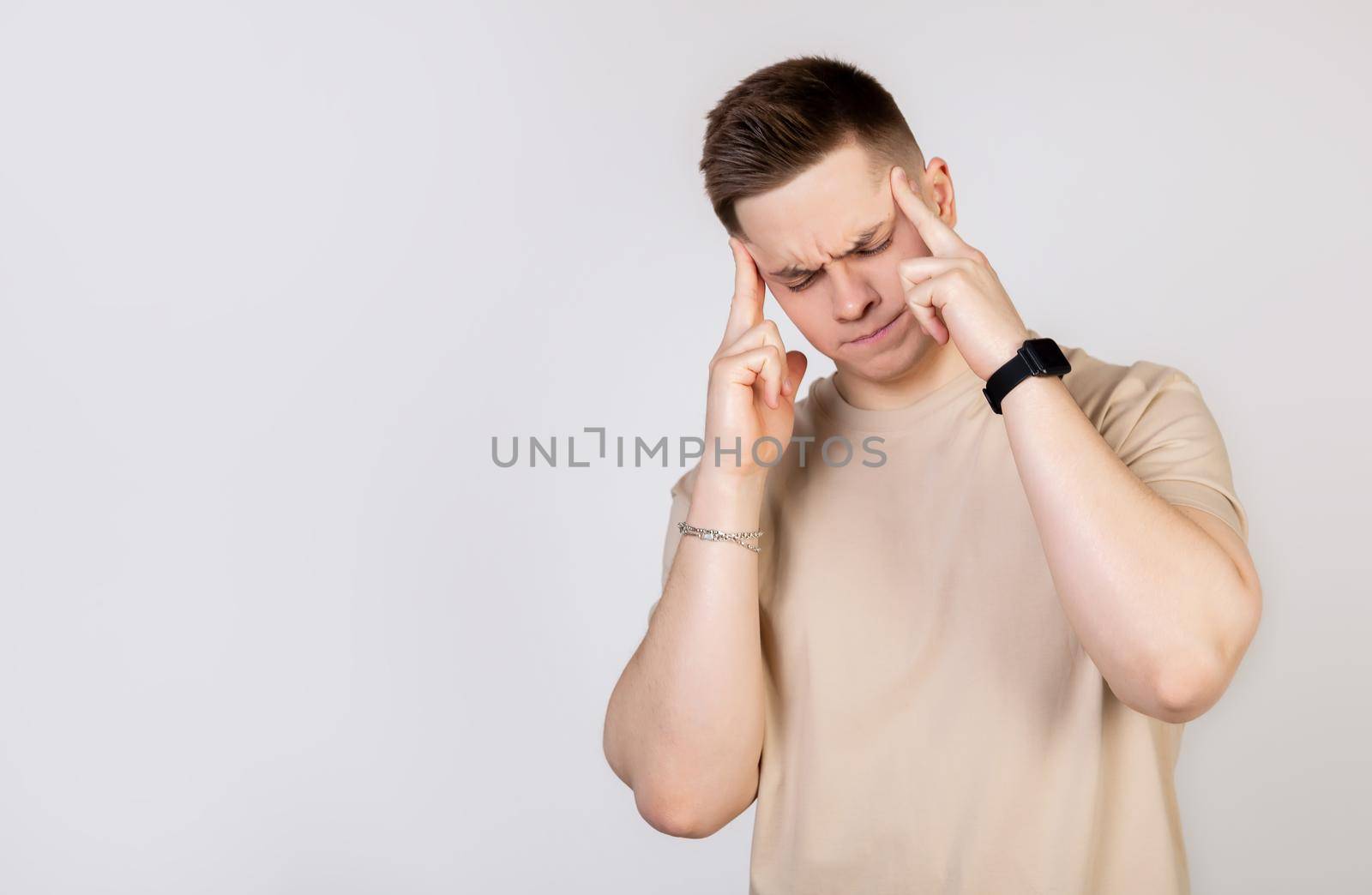 Handsome young man with a fashionable haircut, guy massaging whiskey with his fingers, trying to concentrate on work.