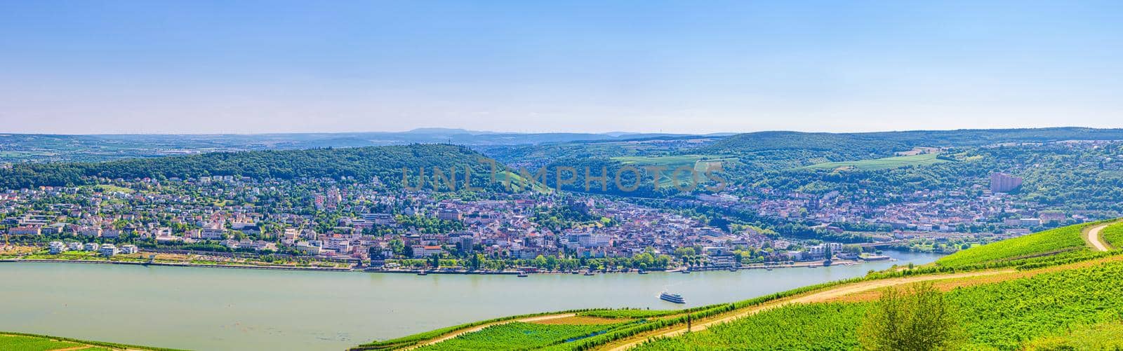 Aerial panoramic view of river Rhine Gorge or Upper Middle Rhine Valley winemaking region with vineyards green fields, Bingen am Rhein town, blue sky, Rhineland-Palatinate, Hesse states, Germany