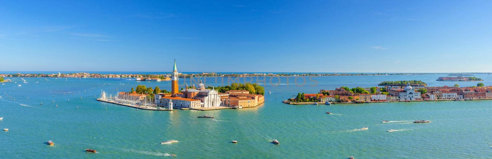 Aerial panoramic view of Venetian Lagoon with San Giorgio Maggiore island, Lido island and Giudecca island, sailing boats in Giudecca Canal, blue sky, Venice city, Italy. Panoram of Venetian Lagoon