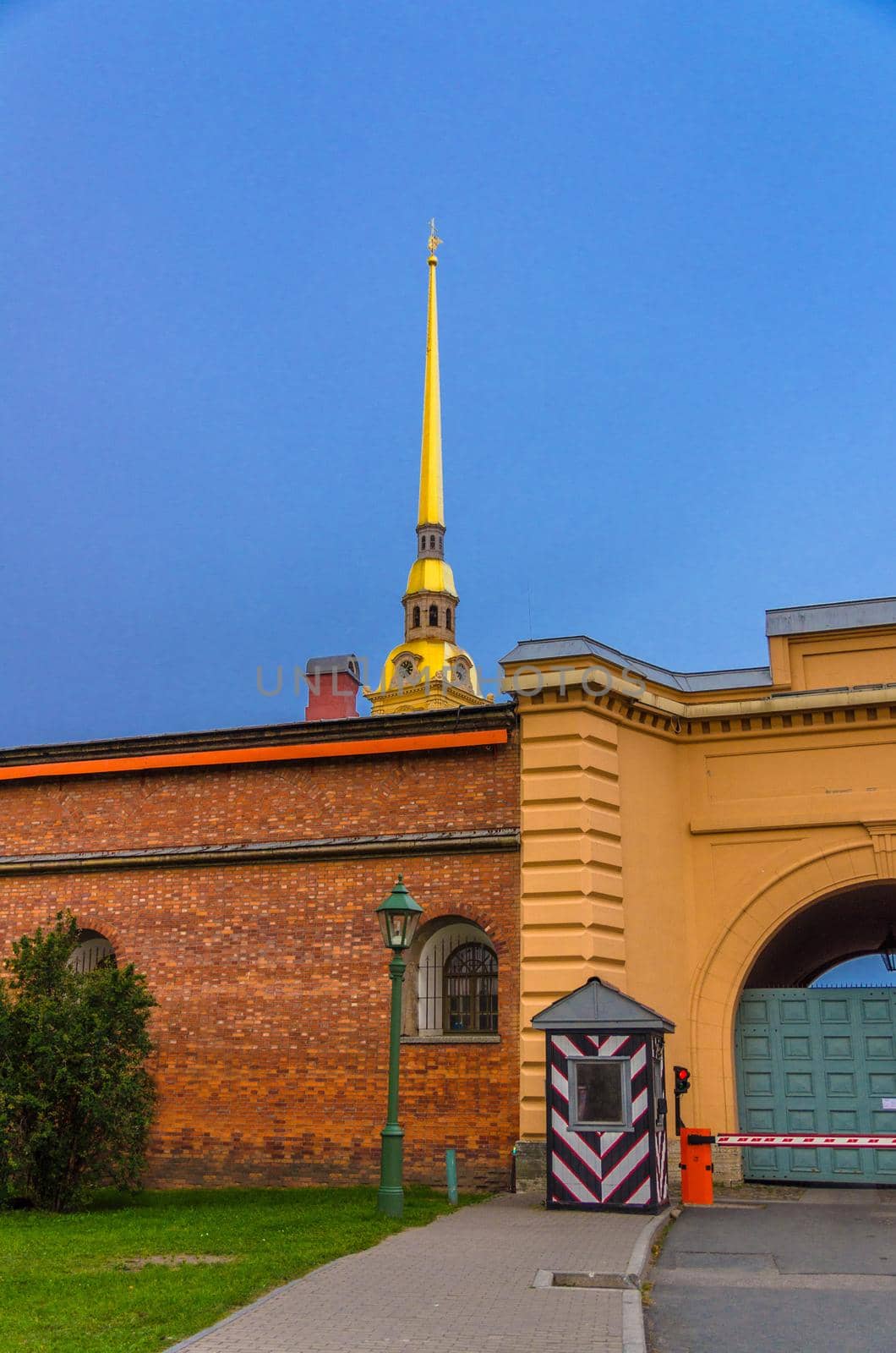 Golden spire of Saints Peter and Paul Cathedral church over brick wall of Peter and Paul Fortress citadel and guardhouse Sentry box on Zayachy Hare Island, Saint Petersburg Leningrad city, Russia