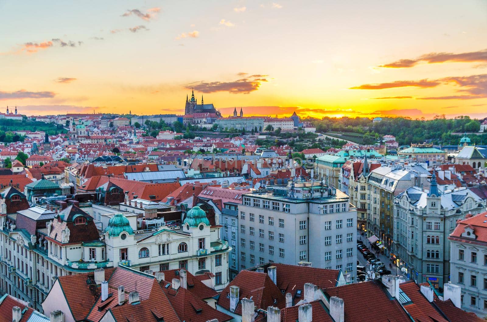 Top aerial panoramic view of Prague Old Town historical city centre with red tiled roof buildings and Prague Castle, St. Vitus Cathedral in Hradcany district in evening sunset, Bohemia, Czech Republic