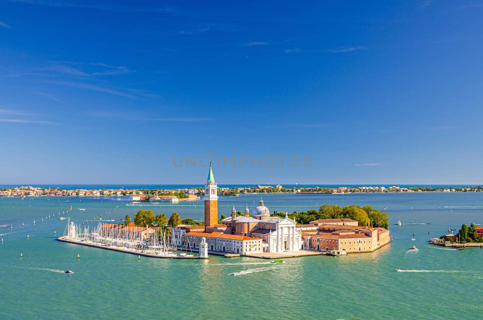 Aerial panoramic view of San Giorgio Maggiore island with Campanile San Giorgio in Venetian Lagoon, sailing boats in Giudecca Canal, Lido island, blue sky background, Venice city, Veneto Region, Italy