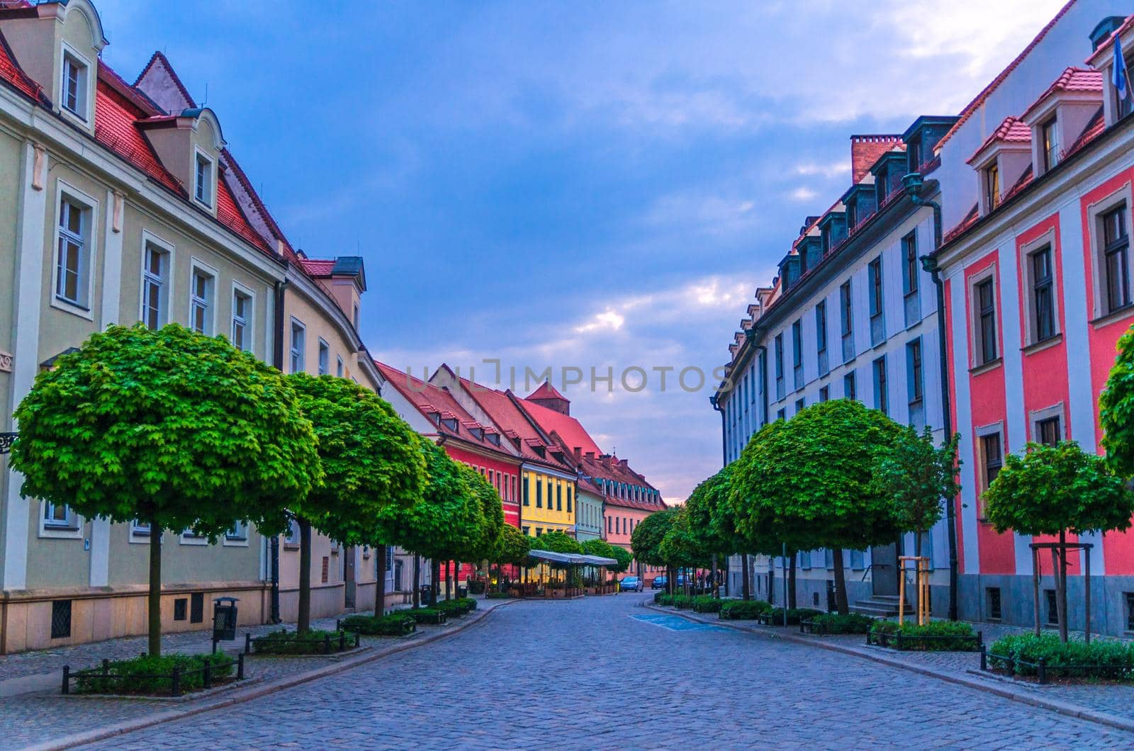 Cobblestone street road with colorful multicolored buildings and green trees in old town historical city centre, evening view, Ostrow Tumski, Wroclaw, Poland