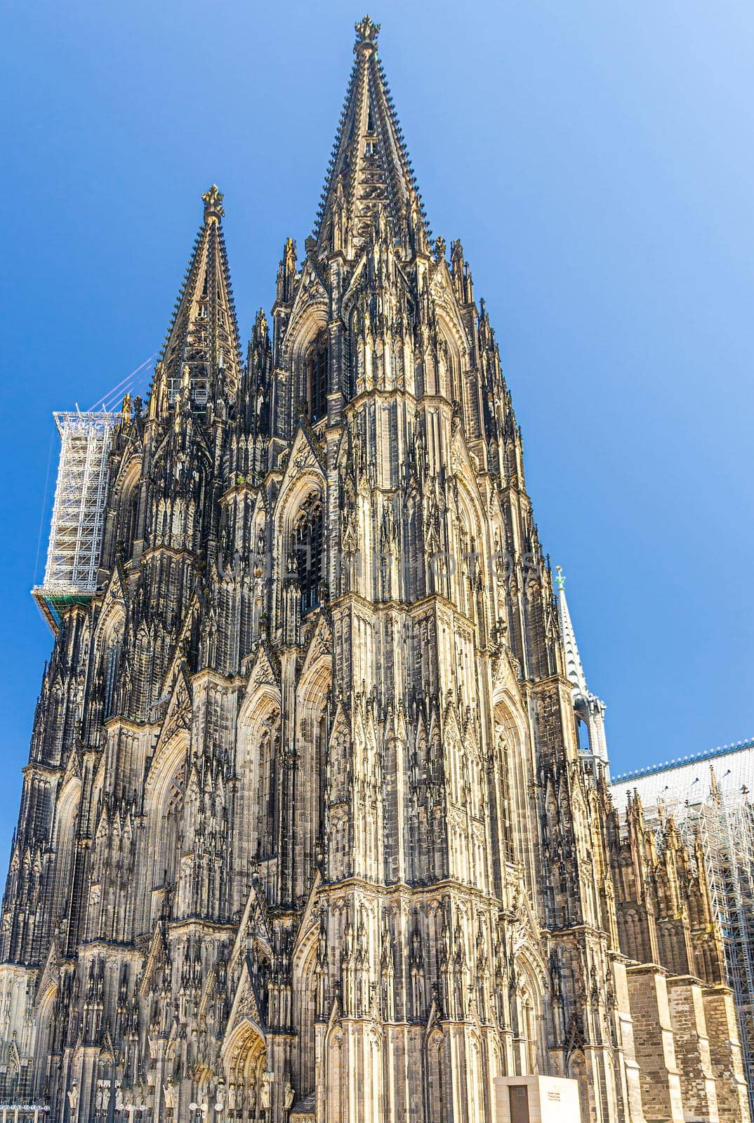 Cologne Cathedral Roman Catholic Church of Saint Peter gothic architectural style building with two huge spires in historical city centre, blue sky in sunny day, North Rhine-Westphalia, Germany