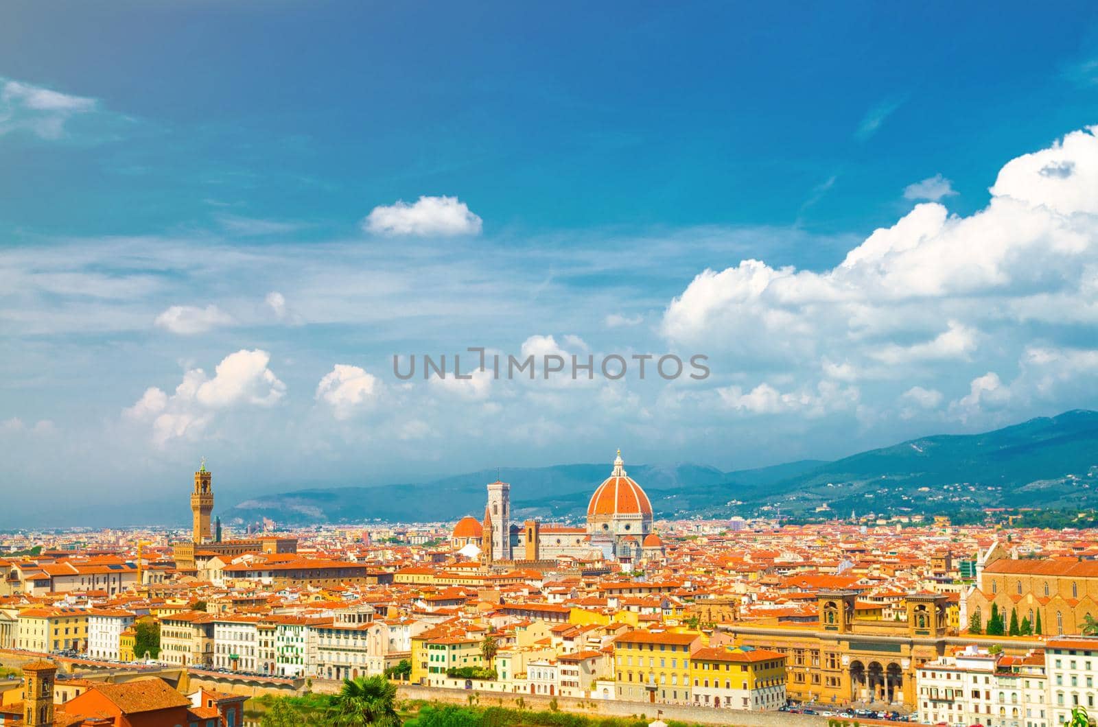 Top aerial panoramic view of Florence city with Duomo Cattedrale di Santa Maria del Fiore cathedral, buildings houses with orange red tiled roofs and hills range, blue sky white clouds, Tuscany, Italy