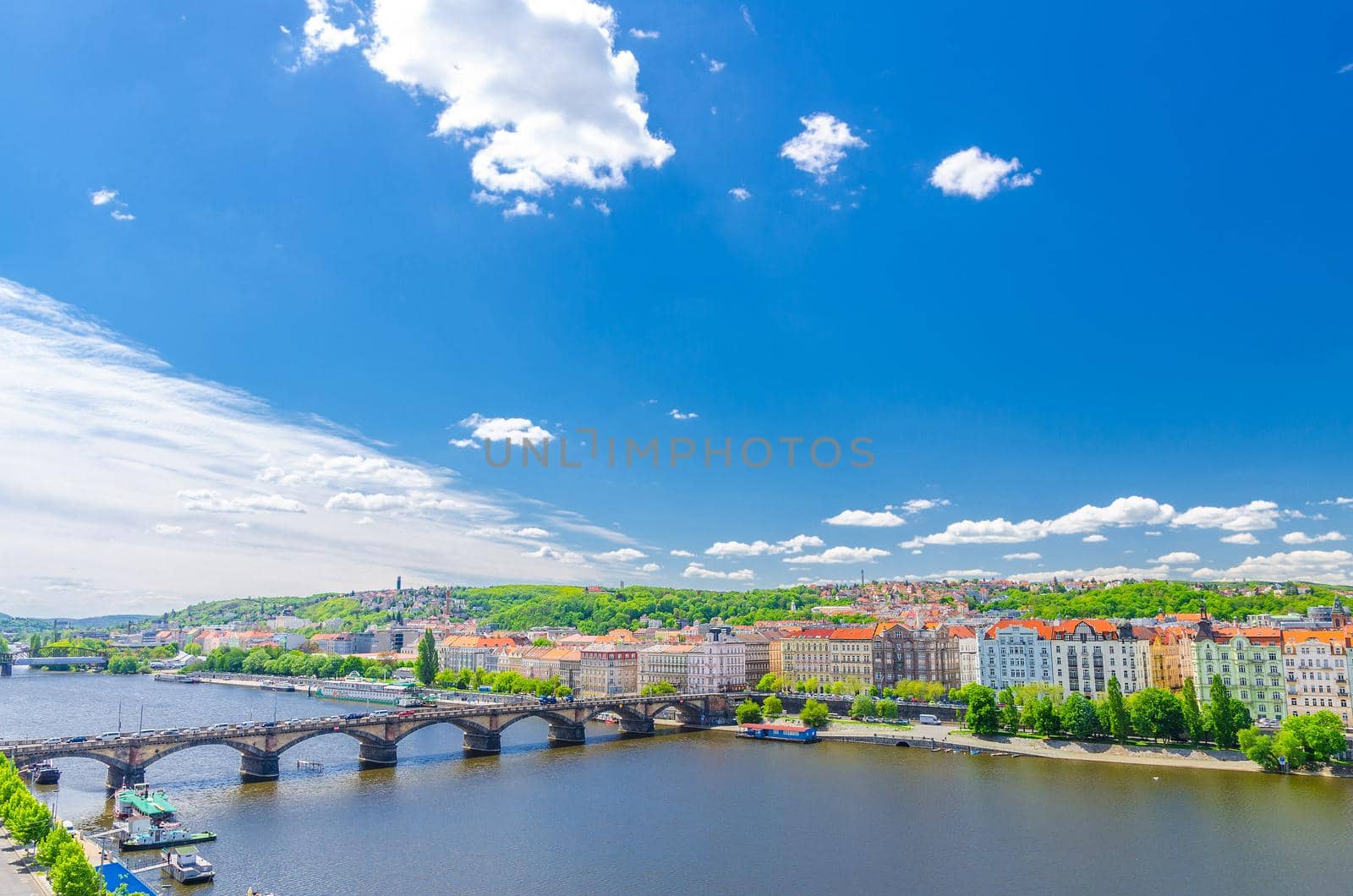 Aerial panoramic view of Prague city, historical center with Smichov district, Palackeho most bridge, row of buildings along Vltava river, blue sky white clouds background, Bohemia, Czech Republic