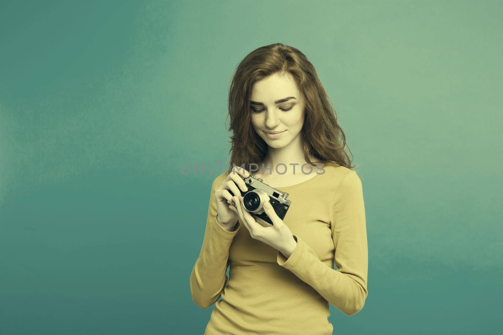Close up Portrait young beautiful attractive ginger girl happy smiling with vintage camera and ready to travel. Blue Pastel Background. Copy space