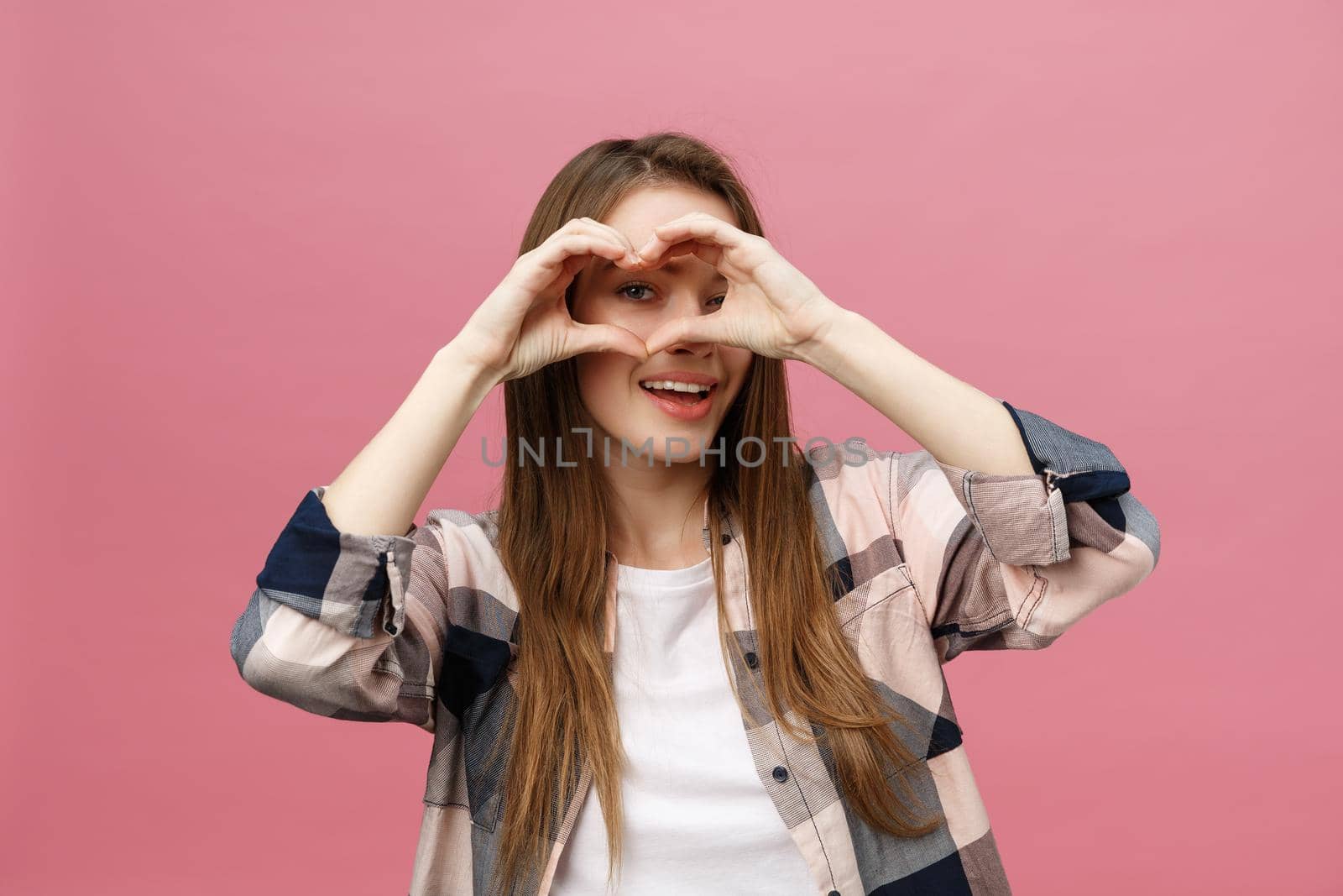 Lifestyle Concept: Beautiful attractive woman in white shirt making a heart symbol with her hands by Benzoix