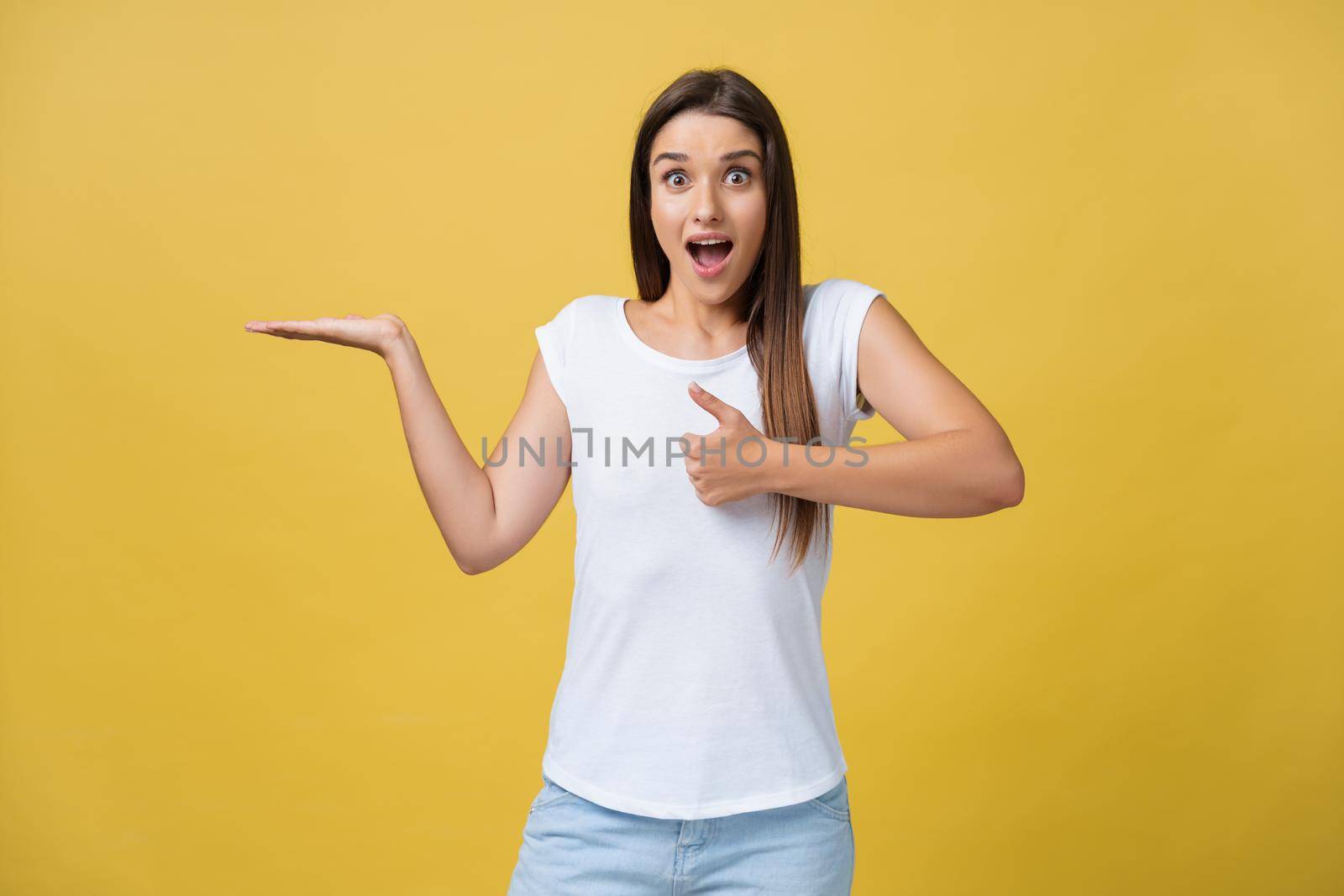 Portrait of magnificent pretty lovely gorgeous adorable stylish cheerful girl in casual white t-shirt, pointing aside with hand and finger, isolated over yellow background.