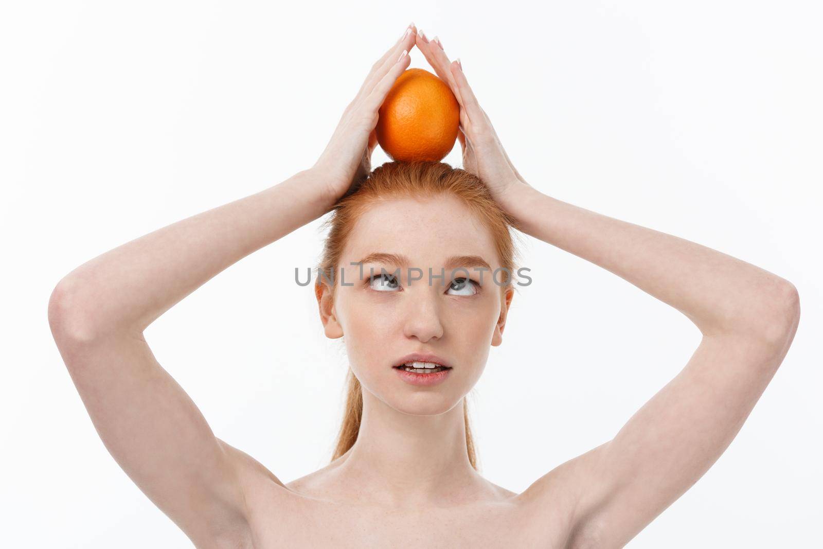 Great food for a healthy lifestyle. Beautiful young shirtless woman holding piece of orange standing against white background