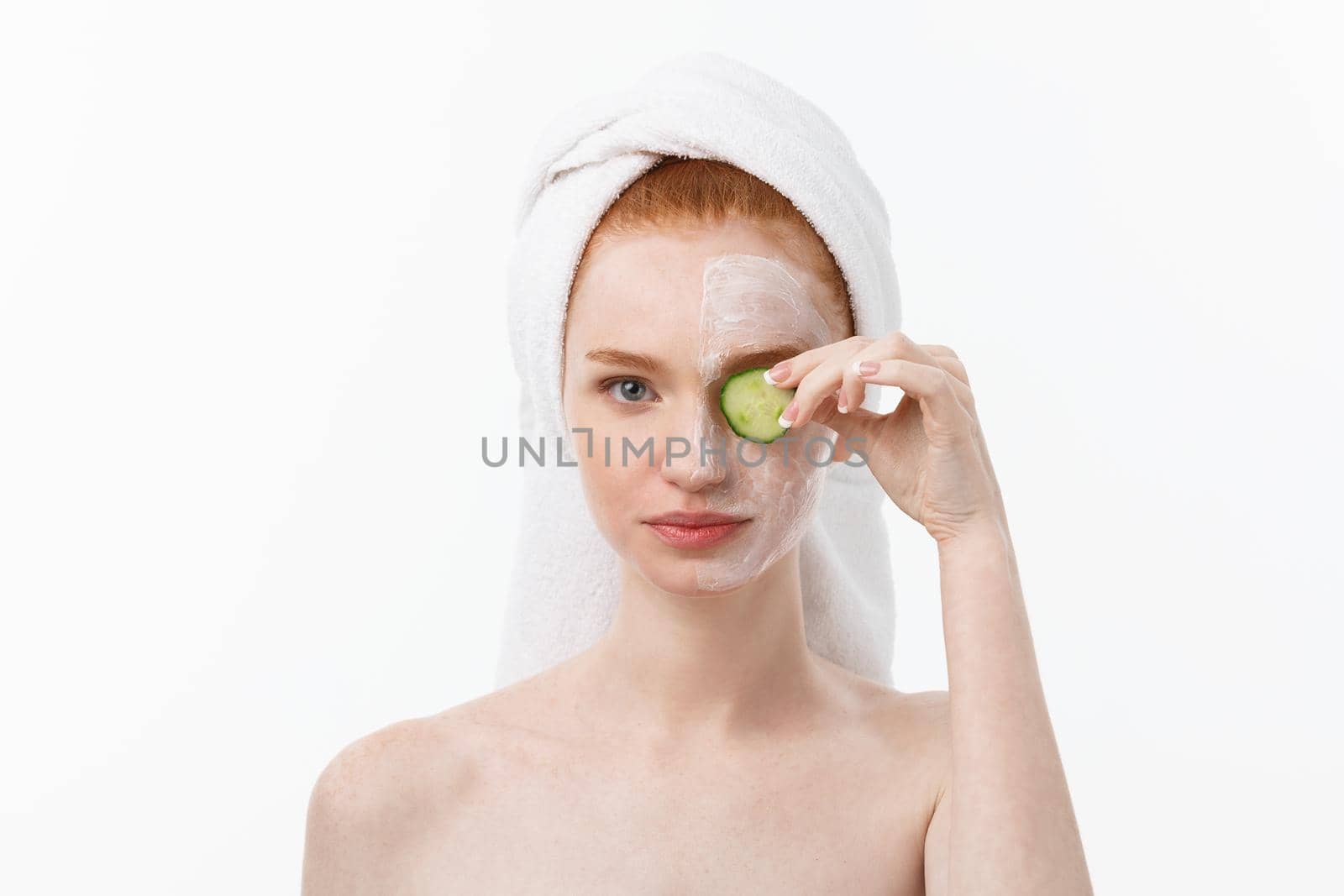 Attractive Young Woman with beautiful clean skin. White mask and cucumbers. Beauty treatments and cosmetology spa therapy. White background by Benzoix