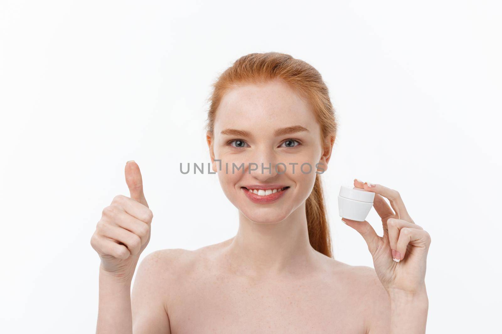 portrait of beautiful woman smiling while taking some facial cream isolated on white background with copy space