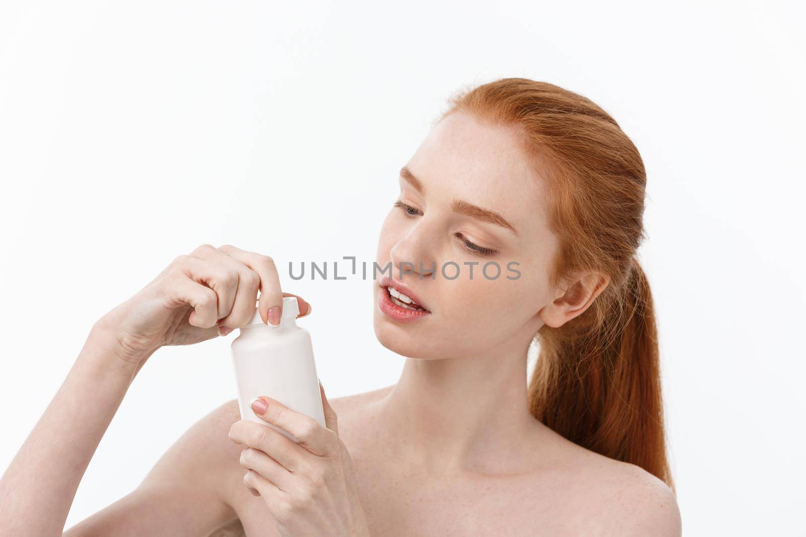 Portrait of good-looking young caucasian woman holding pills, trying to take care of immune system and health over gray background