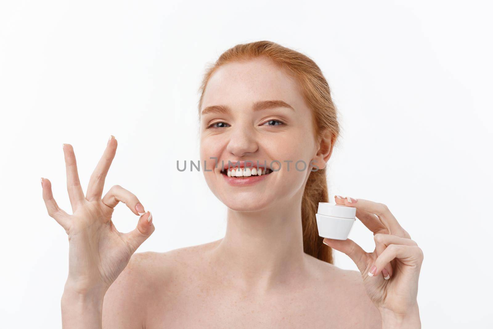 portrait of beautiful woman smiling while taking some facial cream isolated on white background with copy space