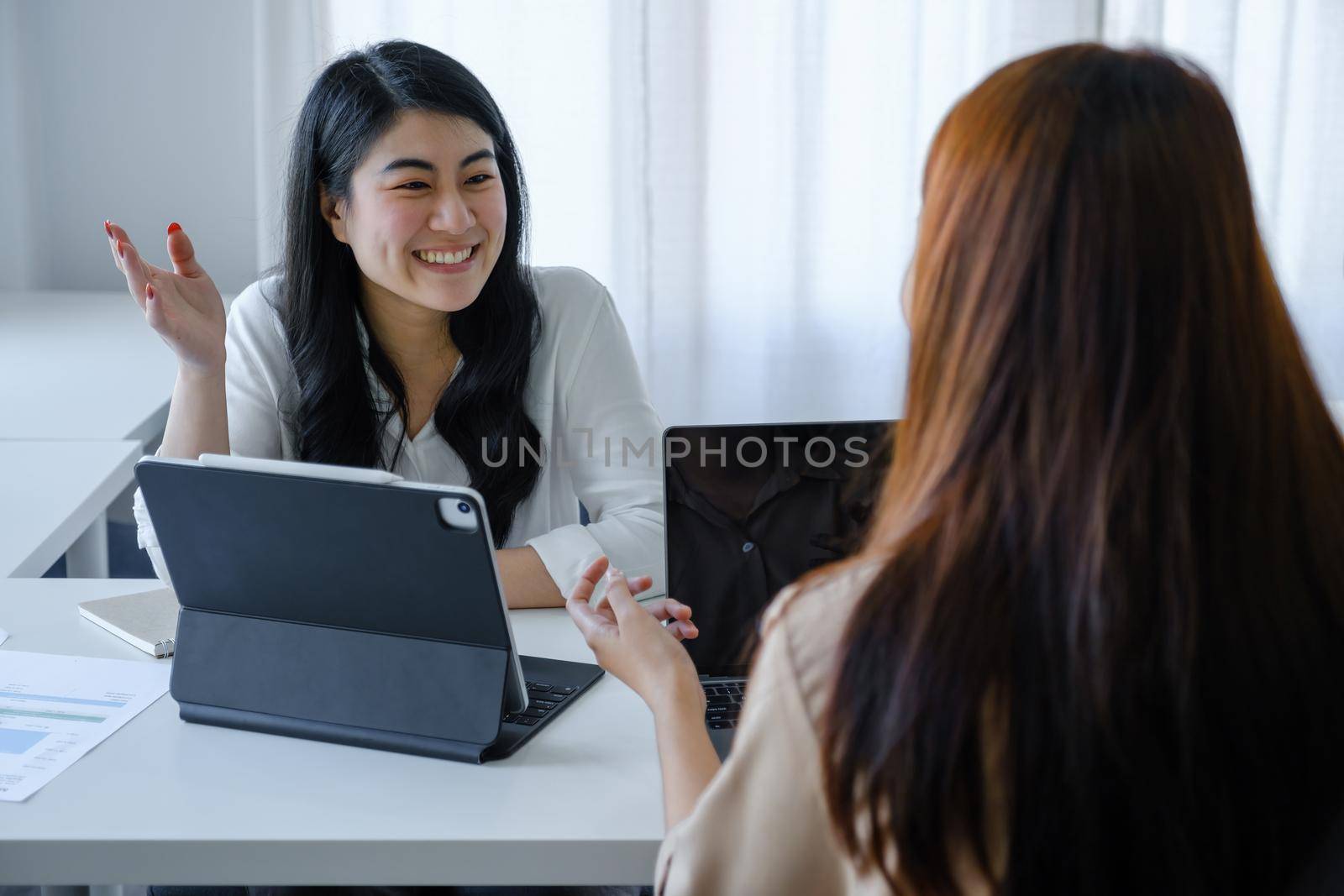 team work concept consultation An economic team analyst is using a tablet to discuss budgets and investments and financial planning with a female advisor in a conference room by Manastrong