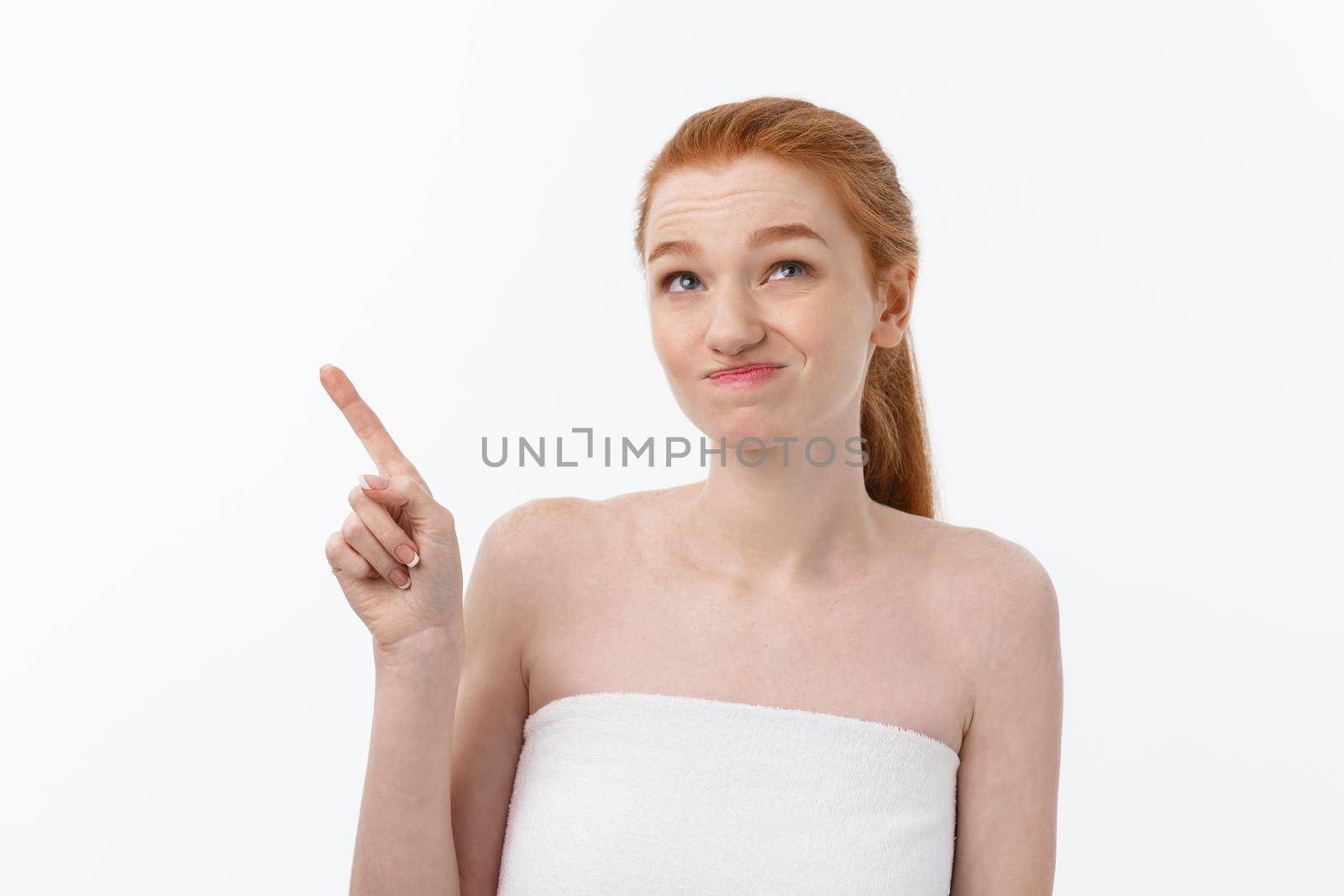 Portrait of caucasian cute in concern and shock, pointing index finger aside, over white background